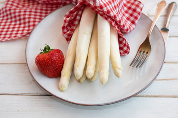 White asparagus and strawberries on a plate with red checkered cloth. Food photography for seasonal...
