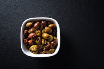 bowl of Taggiasca olives top view. dark stone background