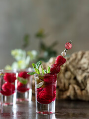 Raspberry vodka glass shot with fruit inside. Fresh summer shots for party. Berries in alcohol glass. Glass of sparkling water.