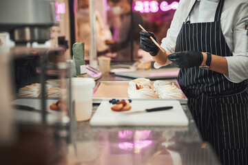 Dedicated pastry chef adding some glaze to fresh meringues
