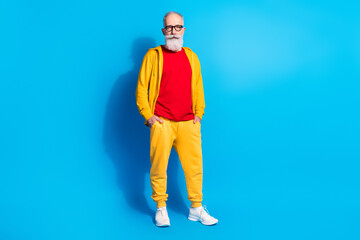 Full size photo of mature handsome good looking serious man wear yellow tracksuit isolated on blue color background