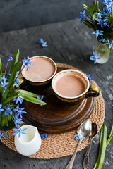 Cocoa in old cups on a table with blue flowers. Hot chocolate drinks. Flat lay.
