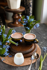 Cocoa in old cups on a table with blue flowers. Hot chocolate drinks. Flat lay.