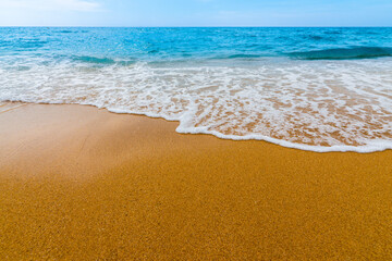 Soft blue ocean wave on clean sandy beach