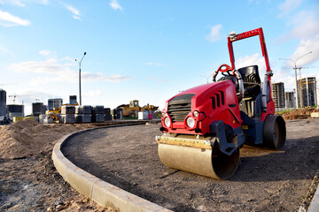 Paving roller machine during road work. Mini road roller at construction site for paving works. Screeding the sand for road concreting. Asphalt pavement is layered over concrete pavement