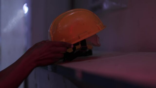 woman worker with security helmet, hands picking up the helmet
