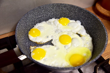 Chicken eggs in a frying pan while frying on the stove. Chicken egg yolk and white