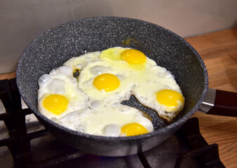 Chicken eggs in a frying pan while frying on the stove. Chicken egg yolk and white