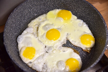 Chicken eggs in a frying pan while frying on the stove. Chicken egg yolk and white