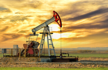 Fototapeta na wymiar Crude oil pump jack at oilfield on sunset backround. Fossil crude output and fuels oil production. Oil drill rig. Crude mining concept. Oil prices on the trading exchange.