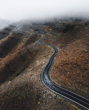 Aerial view of an empty road driving along a volcanic hillside near Mogan, Canary Islands, Spain.