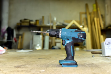 Cordless combi drill for used as impact drill and screw driver. Cordless impact screwdriver for work with self-tapping screws. Brushless battery drill on a wooden workbench in furniture workshop