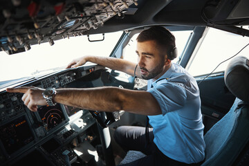 Worried young pilot pointing to something outside the aircraft