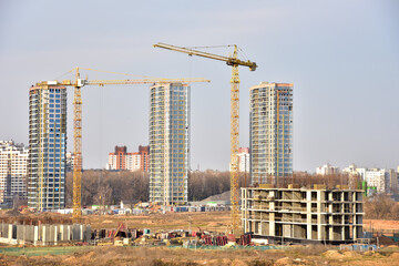Fototapeta na wymiar View of a large construction site. Tower cranes in action. Housing renovation concept. Crane during formworks. Construction the buildings and multi-storey residential homes