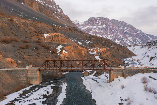 Aerial view of a red bridge crossing the Spiti river at wintertime near Gaza township, Himachal Pradesh, India.