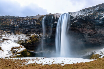 Front view of the Seljalandsfoss waterfall in southern Iceland. This spectacular fall has a 60 metre drop and is part of the Seljalands River. Long exposure.