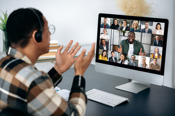 Video call, online conference. Over shoulder view of mixed race man, on computer screen with...