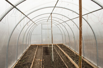 empty greenhouse made of light polycarbonate, no plants, empty beds of land