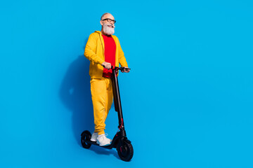 Full length profile portrait of cheerful person look empty space driving moped isolated on blue color background