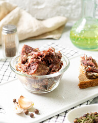 Beef stew in a glass bowl on a light gray table closeup