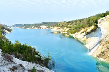 Artificial lake in a chalk quarry in Belarus at Krasnoselsky. Turquoise background of the clear water in summer season in open pit. Technogenic mountains formed during chalk mining. Amazing landscape