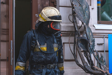 a tired firefighter in a fireproof uniform goes out into the street after a fire.