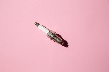 Spark plug. Car candle lies against a pink background. Auto engine electrician. Copy space. Flat lay