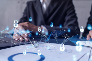 Two businesspeople man and woman working on the project to protect cyber security of international company. Padlock Hologram icons over the table with documents. Formal wear. Workspace.