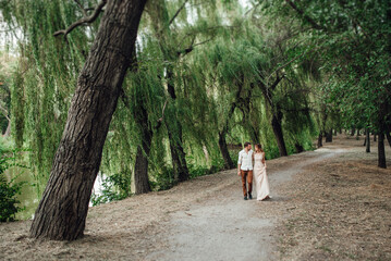 Fototapeta premium a guy and a girl are walking along the banks of a wild river overgrow