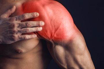 Bodybuilder suffering from shoulder pain on dark background. 