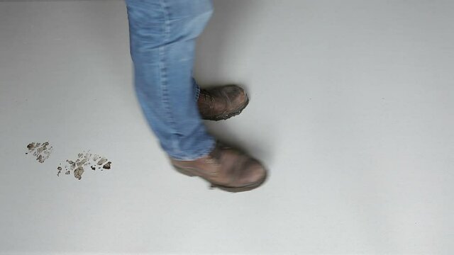 A man in dirty shoes walks across the clean, light floor. The man left traces of dirty shoes. View from above.