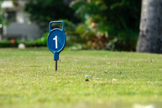 A navy blue circular sign with a white number one, or 1, on its surface. Hole marker on the fairway of a Barbados golf course. Winning, coming out on top concept, singular. 