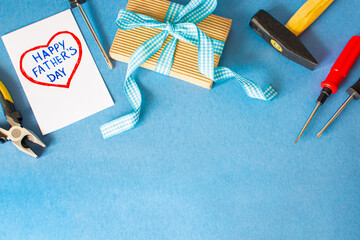 Fototapeta premium Happy father day. Blue background with tools, give dad a present and a heart with the inscription: Happy Father's Day . Copy space for text.