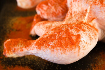 Close up of raw chicken thigh covered in spices prepared for cooking