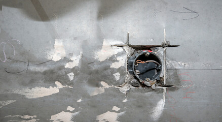 Electrical wire and opened junction box on the concrete wall.  Electrical works on construction site