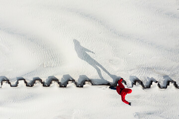 Aerial view of man silhouette shadow balancing on the metal construction in beach, Klaipeda, Lithuania.