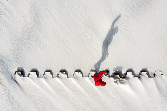 Aerial view of man silhouette shadow balancing on the metal construction in beach, Klaipeda, Lithuania.