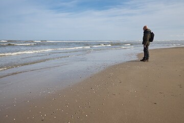 Horizontal landscape of a man standing on the beach, looking towards the sea on a sunny day. With copy space.