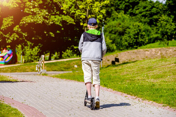 Fototapeta premium A boy rides a scooter in a city Park 