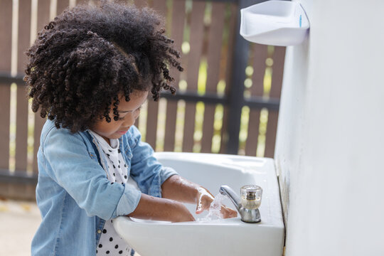 African American children washing hand from faucet running water at outdoor to protect coronavirus epidemic.