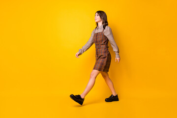 Fototapeta na wymiar Full size profile photo of optimistic brunette lady go wear brown shirt dress boots isolated on vivid yellow background