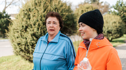 International Day of Older Persons. Portraits of a grandmother with an adult granddaughter walking in the park and talking. Family walks in the park