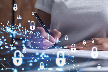 A businesswoman in casual wear signing the contract to prevent probability of risks in cyber security. Padlock Hologram icons over the working desk.