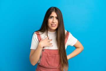 Young caucasian woman isolated on blue background pointing to oneself