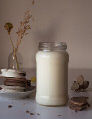 vaso o botella de leche sobre una mesa de color blanco, acompañado de alfajores tradicionales de argentina de dulce de leche con chocolate