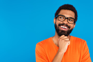 smiling african american man in glasses looking away isolated on blue