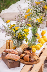 Bread of ciabatta, lemons, flowers on a picnic