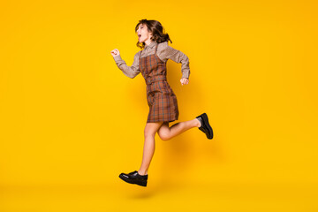 Full size profile photo of optimistic funny brunette lady run hands fists wear shirt dress sneakers isolated on vivid yellow background