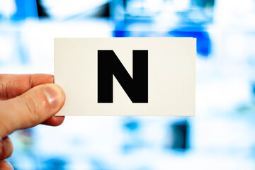 A man holds a business card on the background of the monitor with the letter N