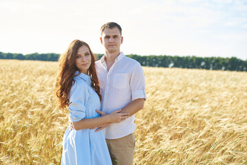 A young couple of lovers women and men hug in nature, in a yellow wheat field. The concept of love, good relationships, understanding and harmony